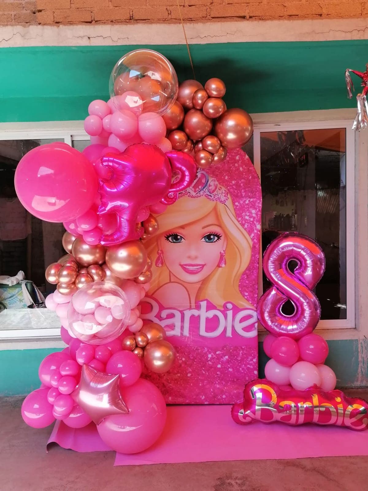 Número 8 metálico rosa sobre columna de globos y letrero Barbie metálico junto a arco tema Barbie